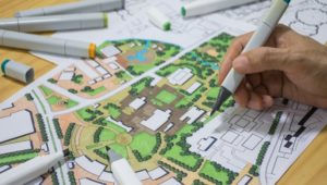 Bilde av hånd som tegner på et grafisk framstilling av by/gateplanlegging i flere farger.