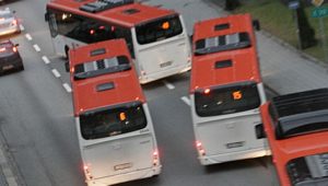 Fire røde og hvite busser på en vei.  Ser ut som de er vekslende på vei inn/ut ift busstopp.